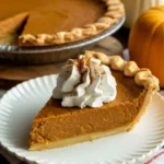 Best pumpkin pie recipe with whipped cream on rustic table